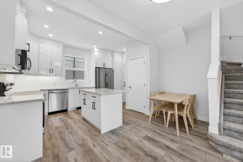 Kitchen with white cabinets, light wood-style flooring, modern cabinets, stainless steel appliances, and recessed lighting - #5 15805 97 Ave, Edmonton, AB - Indoor Photo Showing Kitchen With Upgraded Kitchen