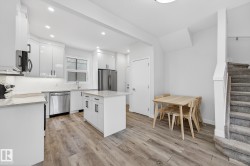 Kitchen with white cabinets, light wood-style flooring, modern cabinets, stainless steel appliances, and recessed lighting - 