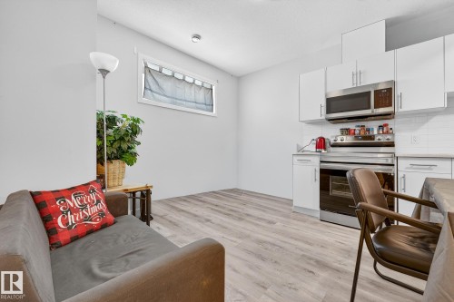 Kitchen featuring stainless steel appliances, white cabinets, light wood-type flooring, and decorative backsplash - #5 15805 97 Ave, Edmonton, AB - Indoor Photo Showing Kitchen
