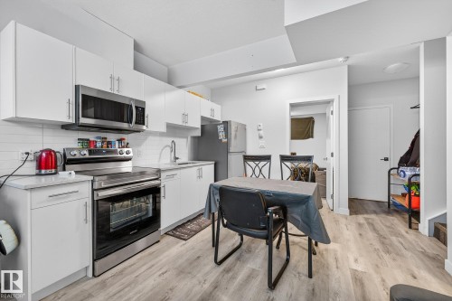 Kitchen featuring stainless steel appliances, white cabinets, backsplash, light wood finished floors, and light stone countertops - #5 15805 97 Ave, Edmonton, AB - Indoor Photo Showing Kitchen