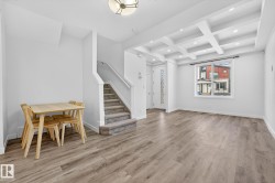 Dining area with coffered ceiling, light wood finished floors, beamed ceiling, stairway, and recessed lighting - 