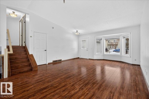 Unfurnished living room with dark wood-type flooring, stairway, lofted ceiling, and a textured ceiling - 2516 42 Street, Edmonton, AB - Indoor