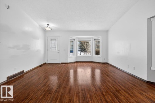 Unfurnished living room featuring dark wood-type flooring and a textured ceiling - 2516 42 Street, Edmonton, AB - Indoor Photo Showing Other Room