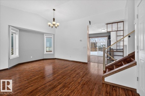 Unfurnished room with dark wood-type flooring, stairs, a chandelier, vaulted ceiling, and a textured ceiling - 2516 42 Street, Edmonton, AB - Indoor Photo Showing Other Room