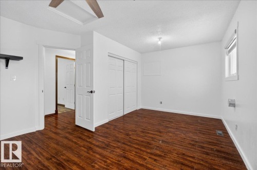Unfurnished bedroom featuring a textured ceiling, dark wood-style flooring, a closet, and attic access - 2516 42 Street, Edmonton, AB - Indoor Photo Showing Other Room
