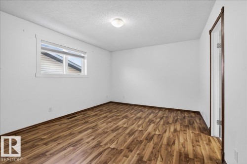 Unfurnished bedroom featuring dark wood-type flooring, a textured ceiling, and a closet - 2516 42 Street, Edmonton, AB - Indoor Photo Showing Other Room