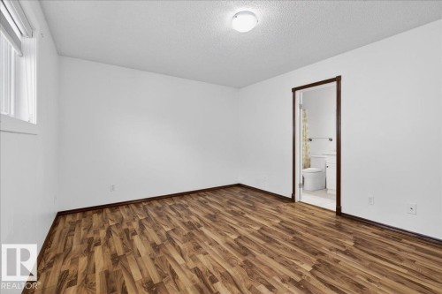 Unfurnished bedroom with dark wood-type flooring, a textured ceiling, and ensuite bathroom - 2516 42 Street, Edmonton, AB - Indoor Photo Showing Other Room