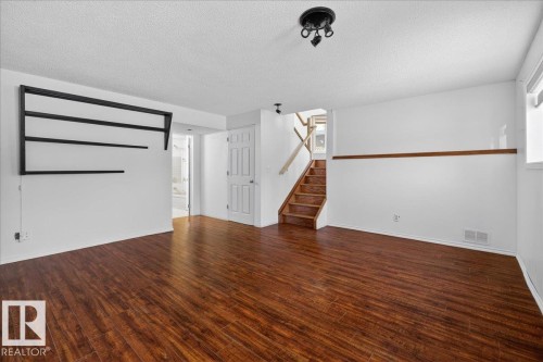 Unfurnished living room featuring stairway, dark wood-style floors, and a textured ceiling - 2516 42 Street, Edmonton, AB - Indoor Photo Showing Other Room