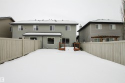 Snow covered house featuring a wooden deck and a fenced backyard - 