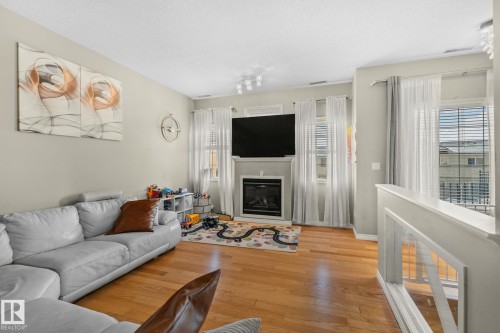 Living area with wood finished floors and a glass covered fireplace - 46 13825 155 Avenue, Edmonton, AB - Indoor Photo Showing Living Room With Fireplace