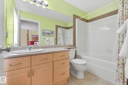 Ensuite bathroom featuring vanity, shower / bath combination with curtain, and light tile patterned flooring - 