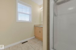 Full bathroom with vanity, a stall shower, and light tile patterned floors - 