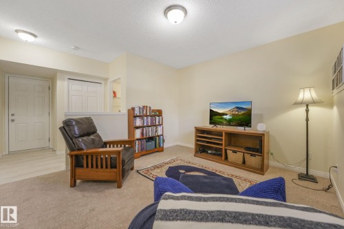 Carpeted living room featuring baseboards and a textured ceiling - 23 4755 Terwillegar Common, Edmonton, AB - Indoor