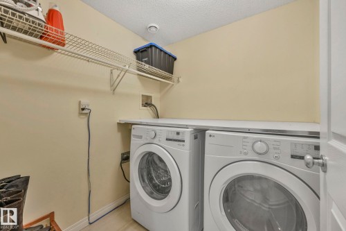 Washroom with a textured ceiling and washing machine and clothes dryer - 23 4755 Terwillegar Common, Edmonton, AB - Indoor Photo Showing Laundry Room