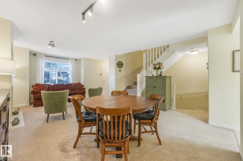Dining room with stairway, light carpet, and track lighting - 23 4755 Terwillegar Common, Edmonton, AB - Indoor Photo Showing Dining Room
