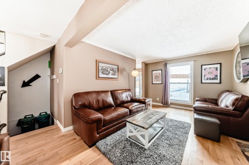 Living room with light wood-type flooring, crown molding, and a textured ceiling - 18931 80 Avenue, Edmonton, AB - Indoor Photo Showing Living Room