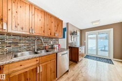Kitchen featuring stainless steel dishwasher, brown cabinetry, decorative backsplash, light wood-style floors, and a textured ceiling - 