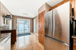 Kitchen featuring freestanding refrigerator, light wood-type flooring, dishwasher, and brown cabinets - 