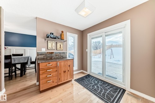 Kitchen featuring brown cabinetry, light wood-style flooring, and dark stone countertops - 18931 80 Avenue, Edmonton, AB - Indoor Photo Showing Other Room