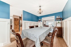 Dining space with light wood finished floors, wainscoting, a chandelier, and a decorative wall - 
