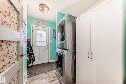 Laundry area featuring stacked washer and clothes dryer, light wood-type flooring, and a textured ceiling - 