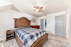 Bedroom with light wood-type flooring, ceiling fan, a textured ceiling, and vaulted ceiling - 