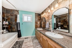 Full bathroom featuring double vanity, shower / tub combo with curtain, light wood-style flooring, and a textured ceiling - 