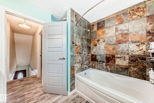 Bathroom featuring tub / shower combination, wood finished floors, and a textured ceiling - 18931 80 Avenue, Edmonton, AB - Indoor Photo Showing Bathroom