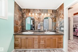 Full bathroom with double vanity, light wood-style floors, and backsplash - 