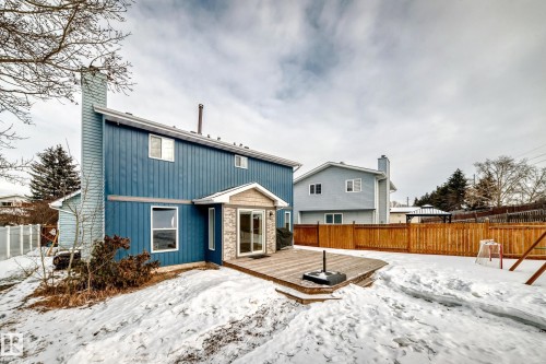 Snow covered rear of property featuring a fenced backyard, a deck, a chimney, and board and batten siding - 18931 80 Avenue, Edmonton, AB - Outdoor