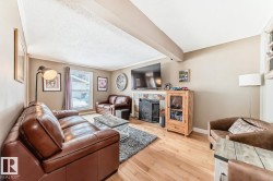 Living room featuring ornamental molding, a fireplace, light wood-style floors, beam ceiling, and a textured ceiling - 