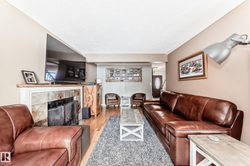 Living room with a fireplace, wood finished floors, ornamental molding, and a textured ceiling - 18931 80 Avenue, Edmonton, AB - Indoor Photo Showing Living Room With Fireplace