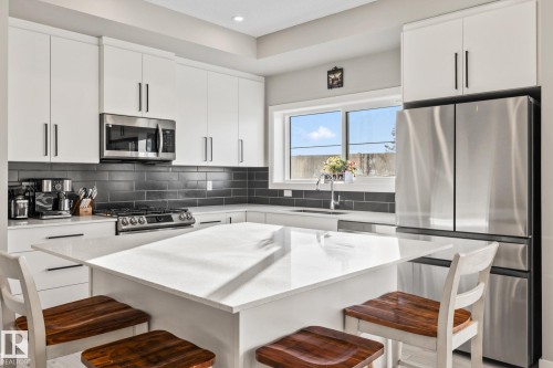Kitchen featuring a kitchen bar, stainless steel appliances, white cabinetry, a center island, and recessed lighting - 217 Larch Crescent, Leduc, AB - Indoor Photo Showing Kitchen With Upgraded Kitchen