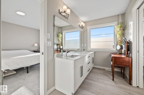 Full bathroom featuring double vanity, connected bathroom, and light wood-type flooring - 217 Larch Crescent, Leduc, AB - Indoor