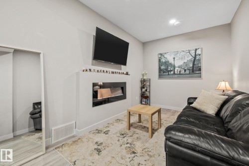 Living area with light wood-type flooring and a glass covered fireplace - 217 Larch Crescent, Leduc, AB - Indoor Photo Showing Living Room With Fireplace