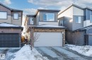 View of front of property featuring stone siding, concrete driveway, and a garage - 217 Larch Crescent, Leduc, AB  - Outdoor 