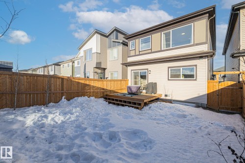 Snow covered back of property with a wooden deck, a fenced backyard, a gate, and a residential view - 217 Larch Crescent, Leduc, AB - Outdoor