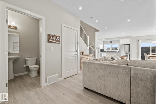 Living room featuring stairs, light wood-style floors, a textured ceiling, and recessed lighting - 217 Larch Crescent, Leduc, AB - Indoor Photo Showing Living Room