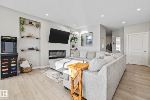Living room featuring light wood-style flooring, a glass covered fireplace, and recessed lighting - 217 Larch Crescent, Leduc, AB - Indoor Photo Showing Living Room With Fireplace