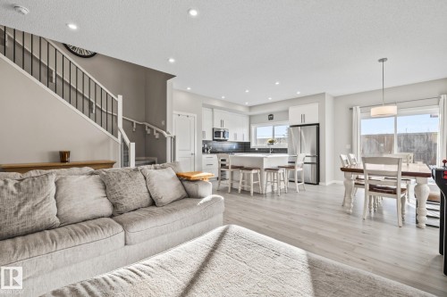 Living room with stairway, a textured ceiling, recessed lighting, and light wood-style flooring - 217 Larch Crescent, Leduc, AB - Indoor Photo Showing Living Room