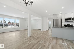 Kitchen with open floor plan, dark stone counters, stainless steel appliances, recessed lighting, and light wood finished floors - 