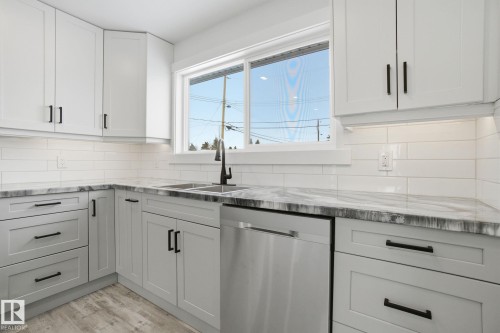 Kitchen with dishwasher, light stone counters, and white cabinetry - 7112 132 Avenue, Edmonton, AB - Indoor Photo Showing Kitchen With Double Sink With Upgraded Kitchen