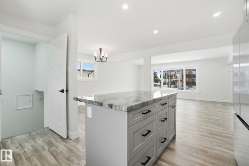 Kitchen with a kitchen island, gray cabinets, freestanding refrigerator, decorative light fixtures, and recessed lighting - 7112 132 Avenue, Edmonton, AB - Indoor Photo Showing Kitchen