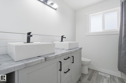 Bathroom featuring double vanity, light wood finished floors, and tasteful backsplash - 7112 132 Avenue, Edmonton, AB - Indoor Photo Showing Bathroom