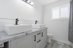 Bathroom featuring double vanity, light wood finished floors, and tasteful backsplash - 