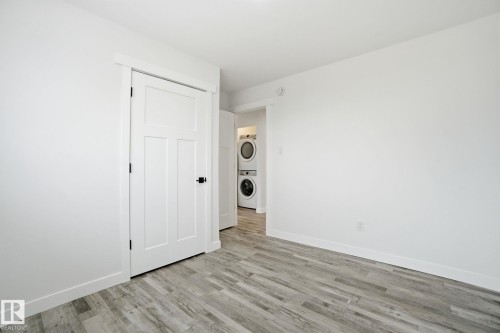 Unfurnished bedroom featuring stacked washing machine and dryer, light wood-style floors, and a closet - 7112 132 Avenue, Edmonton, AB - Indoor Photo Showing Other Room