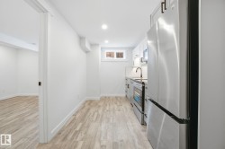 Kitchen with appliances with stainless steel finishes, light wood finished floors, white cabinetry, recessed lighting, and tasteful backsplash - 