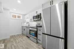 Kitchen with appliances with stainless steel finishes, light wood-style flooring, backsplash, white cabinetry, and gray cabinetry - 