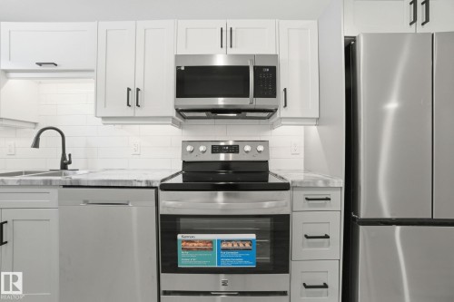 Kitchen featuring stainless steel appliances, tasteful backsplash, and white cabinets - 7112 132 Avenue, Edmonton, AB - Indoor Photo Showing Kitchen With Upgraded Kitchen
