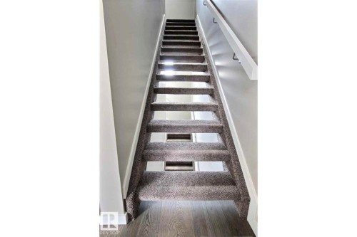 Staircase with wood finished floors and baseboards - 125 1304 Rutherford Road, Edmonton, AB - Indoor Photo Showing Other Room